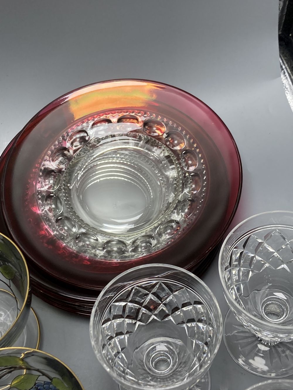 A collection of clear and coloured glassware, including four green bowled wines, vine etched cranberry tumblers, dessert bowls etc.